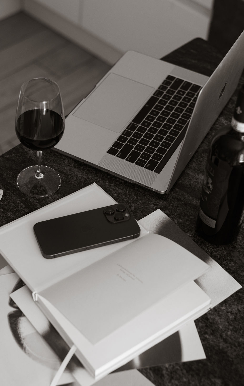 Laptop, wine glass, and journal on a dark counter